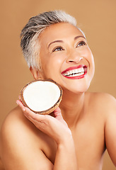 Image showing Coconut, skincare, face and diet wellness keeps her happy and healthy for skin healthcare, eat healthy fruit with nutrition. Portrait of a beauty senior woman in studio against a brown background