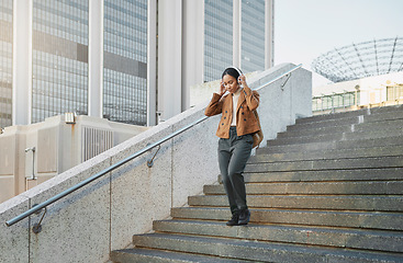 Image showing Music, stairs and city with a business black woman walking outdoor while using headphones for streaming audio. Steps, commute and listening with a female employee streaming audio in an urban town