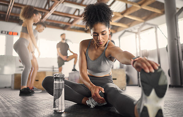 Image showing Black woman, fitness and stretching in gym to workout, exercise or training for health, self care and wellness. Woman, legs and warm up for energy with sports shoes, focus and strong body performance