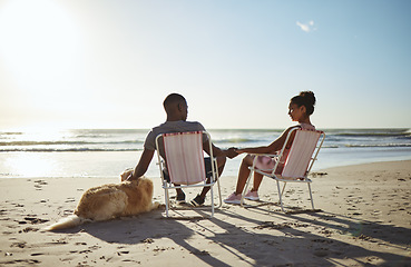 Image showing Black couple, dog and sunset beach while on chair to relax on vacation holding hands for love, care and trust by ocean for quality time. Pet with man and woman in healthy marriage on holiday by sea