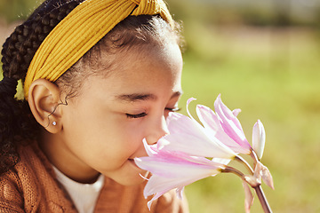 Image showing Nature, beauty and child smell flower in park, enjoying weekend, holiday and vacation in countryside. Peaceful, freedom and young black girl smelling aroma or scent of plant on field in spring time