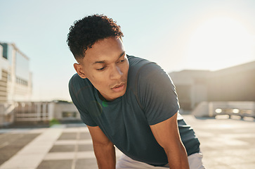 Image showing Runner, fitness and tired man in a city fatigue from running exercise, cardio workout or training. Breathing, fatigue and healthy sports athlete relaxing or resting on a break from marathon training