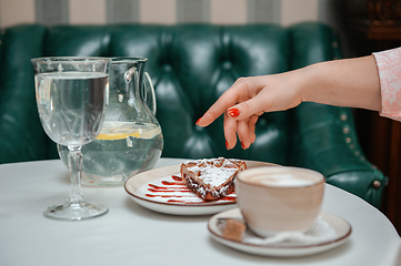 Image showing Closeup photo of female hands is reaching out to cake