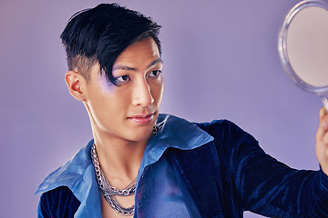 Image showing Asian man with glitter makeup, mirror for creative beauty and lgbt gender performance in fantasy art. Purple background in studio, punk fashion jewellery in Seoul and proud of unique fluid identity