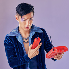 Image showing Purple fashion, telephone and model confused with retro and vintage 1980s telecom device or phone call decline. Punk glitter design, eyeshadow sparkle and creative asian man with gen z beauty makeup