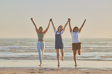 Image showing Holding hands, friends and women on beach, jump together and bonding or loving outdoor on summer vacation. Travel, young females or ladies enjoy seaside holiday, for girls trip and connect on break.