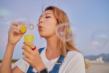 Image showing Asian summer, woman with bubbles and blow liquid soap with lips in outdoor nature freedom with beauty face. Young girl playing with party toy, fun magic on beach mockup and blonde hair in Seoul wind