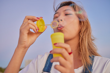 Image showing Asian, soap and bubbles of woman youth enjoying vacation, freedom and wellness on peaceful evening. Calm, relax and peace of girl in Japan blowing bubbles with tranquil sunset sky in summer.