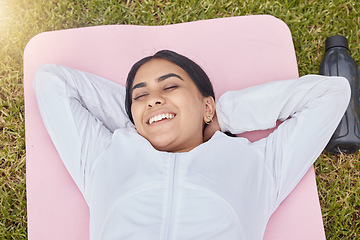 Image showing Happy woman lying on exercise mat in park, garden and grass field for peace, sleep and motivation for workout, training and fitness. Indian girl rest on yoga mat in nature, wellness and healthy life