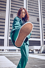 Image showing Fashion, city and model with a black woman on a rooftop, kicking air in contemporary clothing. Street style, portrait and confidence with an attractive young female outdoor to promote trendy style