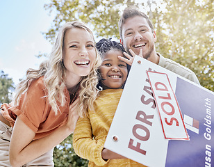 Image showing Family, adoption and homeowner with a girl and foster parents holding a sold sign in their garden or yard. Portrait, diversity and love with a mother, father and daughter celebrating outdoor together