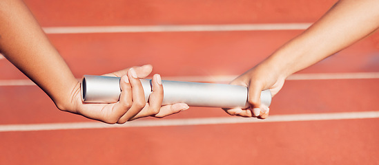 Image showing Hands, baton and relay with a sports woman and partner running a race with teamwork on a track. Fitness, health and exercise with a female athlete team racing in an athletics arena for competition