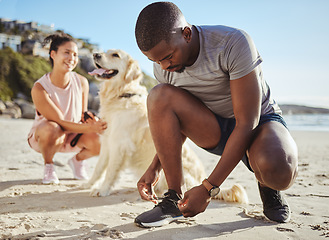 Image showing Fitness, walk and couple at the beach with their dog for freedom, exercise and relax during summer. Wellness, nature and black man tying shoelace by the sea before running with his pet and girlfriend