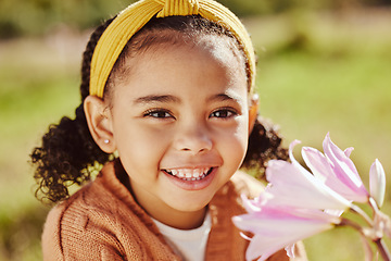 Image showing Flower, happy and girl face in spring portrait with beautiful plant of outdoor in garden or park in summer. Young child enjoying sweet and natural scent of bright floral petals in backyard with smile