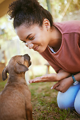 Image showing Happy black woman, pet puppy and play in garden, backyard or park for training, learning and behaviour. Woman, young dog and sitting on grass together for game, fun and happiness outdoor in nature