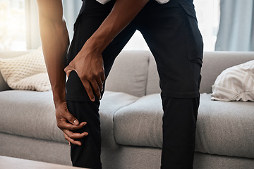 Image showing Black man, hands and knee injury in pain at home from accident, torn muscle or joint ache by living room sofa. African American male suffering from injured leg holding painful area, bruise or bone