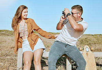 Image showing Couple outdoor, man and woman with camera for photo, happiness and adventure together in nature. Photography, skateboard and road trip with happy, smile and pose on vacation, holiday or travel in sun