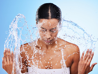 Image showing Water splash, cleaning and woman with water, facial clean and skincare hygiene, wellness and health in blue studio background. Skin, luxury cosmetics and beauty model with washing makeup in studio.