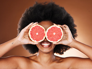 Image showing Beauty, skincare and black woman with grapefruit in hands for natural cosmetics and vitamin c facial treatment with studio background. Happy, smile and fruit covering eyes, wellness and healthy skin.