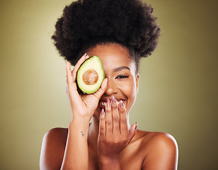 Image showing Black woman, laughing or avocado skincare on green studio background for healthcare diet, dermatology wellness or nutrition. Portrait, smile or happy beauty model with fruit as organic facial product