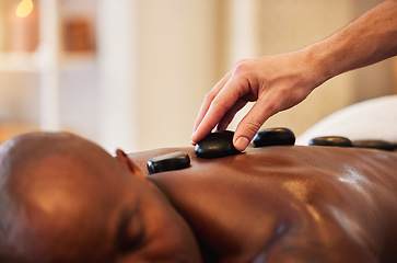 Image showing Massage, therapy and hot stone for wellness and black man, massage therapist hand and wellness spa closeup. Skin, skincare and holistic health for stress relief and relax, self care and body care.