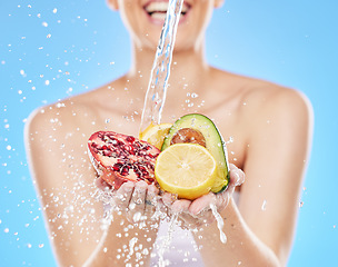 Image showing Water, hands and woman with fruit in studio on blue background for nutrition, wellness and health. Girl washing, cleaning and rinse fruits and vegetable for natural, fresh and organic ingredients