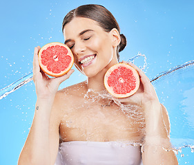 Image showing Woman, water splash or healthy grapefruit in skincare grooming, vitamin c treatment or dermatology on blue background studio. Beauty model, smile or fresh citrus food for organic hydration wellness