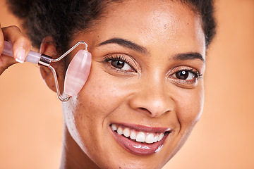 Image showing Massage, smile and black woman with a jade roller for facial health, wellness and beauty against orange studio background. Spa, skincare and face portrait of a model with a product for healthy skin