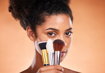 Image showing Makeup, brushes and portrait of a black woman in a studio doing a beautiful, natural and cosmetic routine. Cosmetics, beauty and young female model with facial products isolated by orange background.