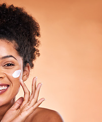 Image showing Skincare, beauty and black woman with facial cream on orange background studio for wellness. Makeup, cosmetics and half face of girl apply lotion, sunscreen and skincare products for dermatology care