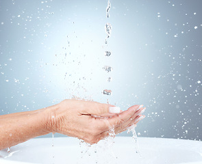 Image showing Water splash, studio and woman cleaning hands in sink or basin on blue background with mockup. Hygiene, health and mature female model washing hands for wellness, skincare and safety from bacteria.