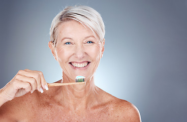 Image showing Smile, dental and senior woman brushing teeth for healthcare, wellness and breath against a grey mockup studio background. Happy, healthy and portrait of an elderly model with toothpaste for breath