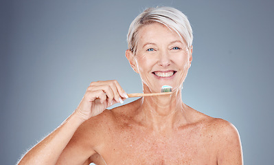 Image showing Teeth, dental care and mature woman brushing teeth with toothbrush and toothpaste on gray background with smile on face. Morning routine, healthcare and fresh, happy senior lady in studio portrait.