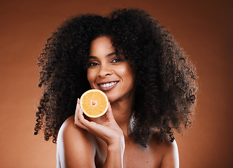 Image showing Orange, health and face of a black woman with fruit for skincare, nutrition and marketing against a brown studio background. Advertising, vitamin c and African model with food for nutrition and detox