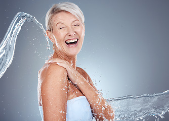 Image showing Water splash, health and portrait of senior woman laughing and happy on gray background with mockup space. Skincare, wellness and beauty, mature lady splashed with water with smile on face in studio.