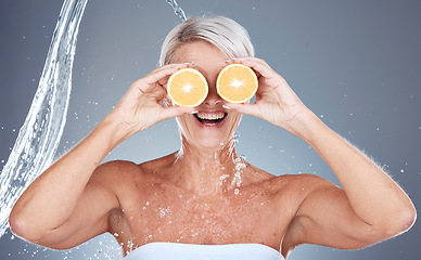 Image showing Water splash, fruit and senior skincare of a woman holding orange for vitamin c and skin glow. Beauty, clean detox and cosmetic health wellness of a model happy about shower, diet and nutrition