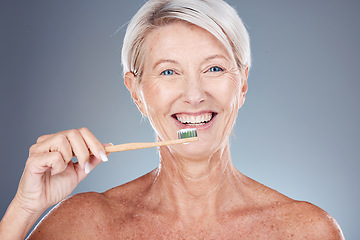 Image showing Dental, studio and senior woman brushing teeth on a gray background. Oral health, wellness and routine of elderly female from Canada holding toothbrush and cleaning teeth for hygiene and oral care