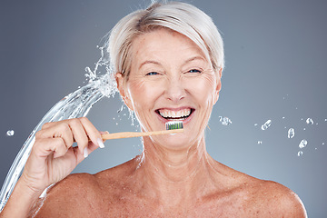 Image showing Wellness, water splash and portrait of old woman brushing teeth isolated on gray background in studio. Bamboo, dental care and senior female cleaning teeth with toothbrush for eco friendly hygiene