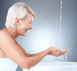 Image showing Senior woman, water splash and cleaning hands in a basin for hygiene against a grey studio background with mockup space. Elderly model washing hand for, health, bacteria and clean body with liquid