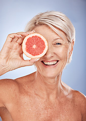 Image showing Face portrait, skincare and old woman with grapefruit isolated on a blue studio background. Smile, happy and elderly female model holding fruit for natural vitamin c, facial care and skin wellness.