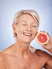 Image showing Grapefruit, skincare and senior woman with food for beauty, aging and wellness against a grey studio background. Smile, healthy and excited elderly model with a fruit with nutrition for body