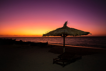 Image showing Vibrant red sky at sunset on Anakao beach in Madagascar, with a tropical parasol and sun lounger