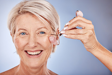 Image showing Skincare, face roller and senior woman with a beauty, natural and fresh skin routine in a studio. Cosmetics, face and portrait of elderly lady with a facial tool doing a cosmetic anti aging treatment