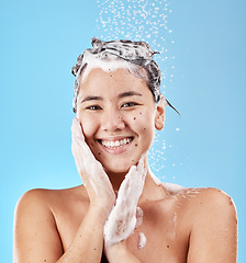 Image showing Woman, shower and for hygiene being clean and with smile for wellness against blue studio background. Portrait, water and Asian female or girl happy, with shampoo and skincare for health or body care