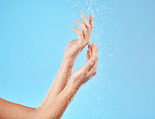 Image showing Hand, water and cleansing for health, wellness and bodycare on a blue studio background. Hands, fingers and shower cleaning of body and arms for cleansing, hygiene and grooming flow