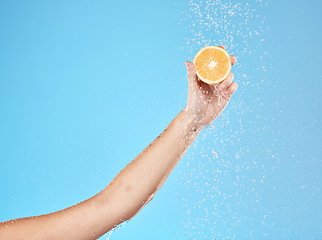 Image showing Lemon, water and hand of woman with fruit for health, beauty and wellness against blue mockup studio background. Cleansing, nutrition and person with vitamin c while showering for a detox with space