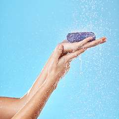 Image showing Shower, water splash or soap in hands for health, cleaning or wash bacteria in blue background studio. Water, clean or zoom of model hand with skin product, wellness skincare luxury cosmetic soap bar