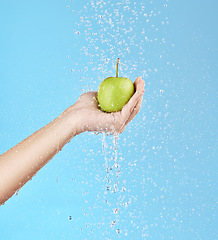 Image showing Apple, hand and health nutrition with water cleaning fruit with wellness, diet or fruit model for advertising. Detox, natural and healthy lifestyle person with blue studio marketing and splash mockup