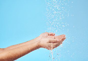 Image showing Shower, water and hands of a woman cleaning, saving and catching liquid against blue studio background. Sustainability, wellness and person with care for body, grooming and hygiene with mockup space