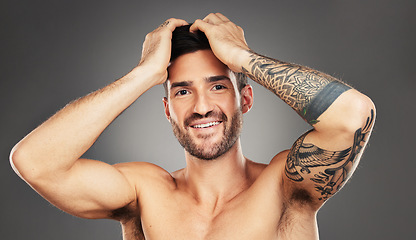 Image showing Face, tattoo and beauty with a man model in studio on a gray background for wellness with confidence. Portrait, happy and smile with a handsome young male posing to promote skincare treatment